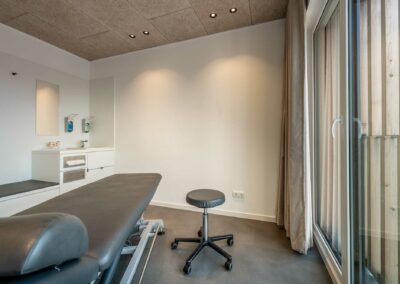 Behandlungsraum in der Praxis für Physiotherapie Physiowerk in Höhr-Grenzhausen mit großen bodentiefen Fenstern und Holzdecke